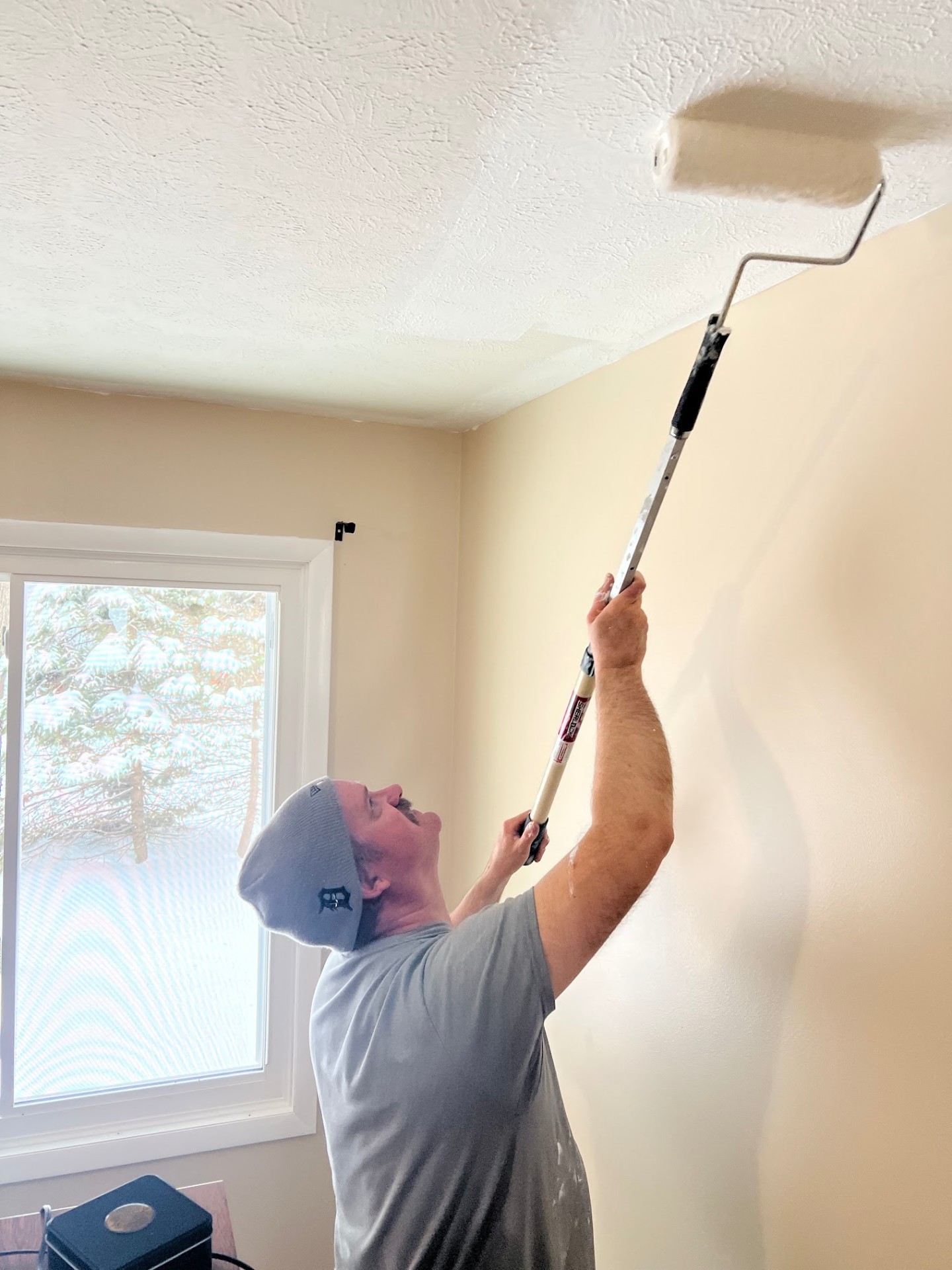 Painter cutting in a ceiling near the wall line